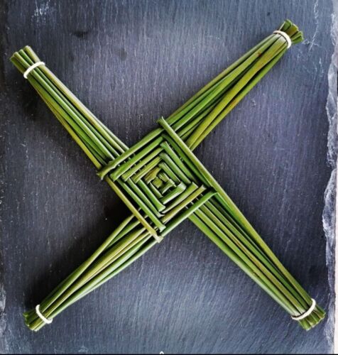 Green straws are laid next to each other and woven into a four point cross on its side