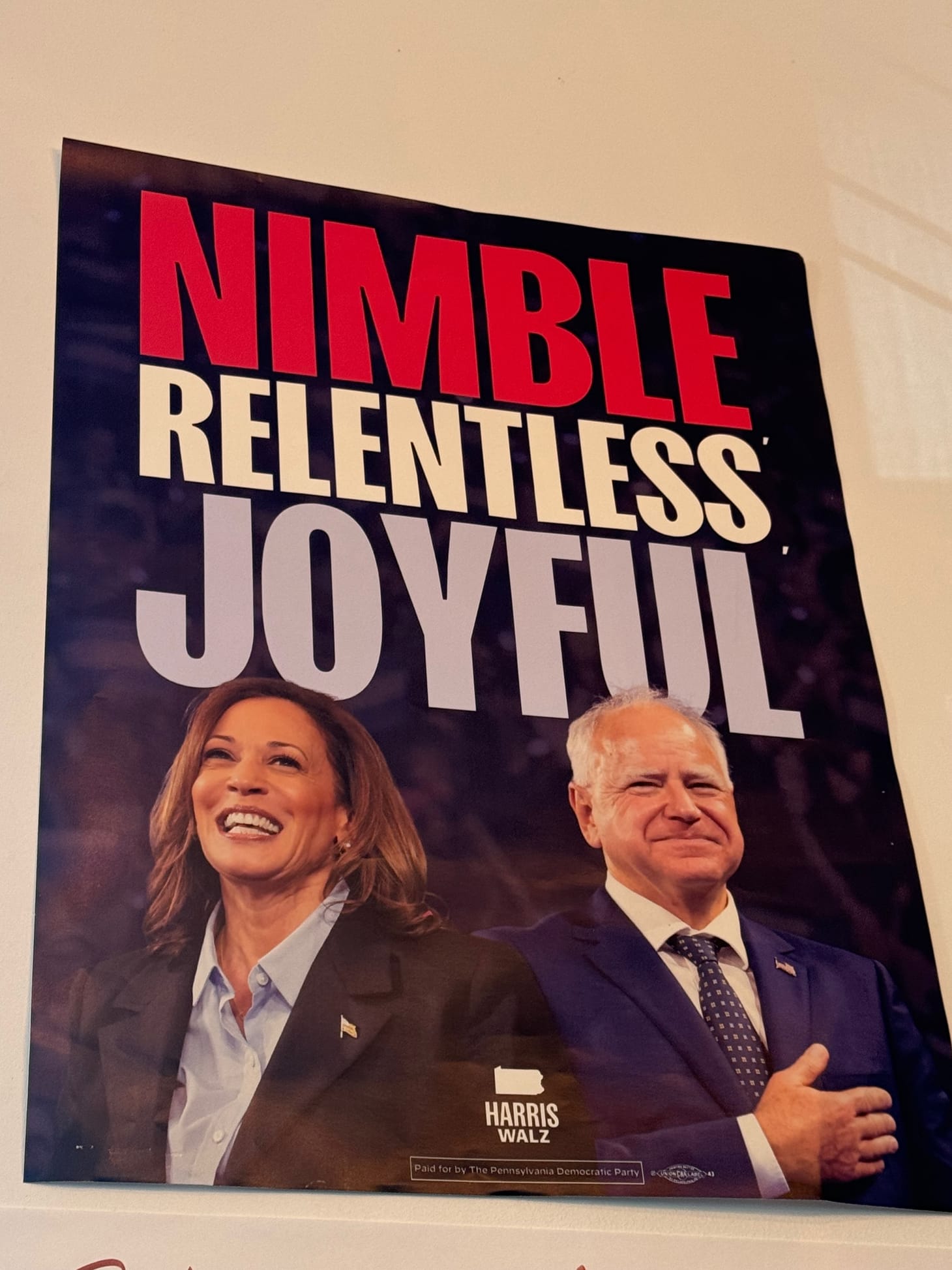 Picture of a poster with the words NIMBLE, RELENTLESS, JOYFUL above a picture of a smiling Kamala Harris and Tim Walz